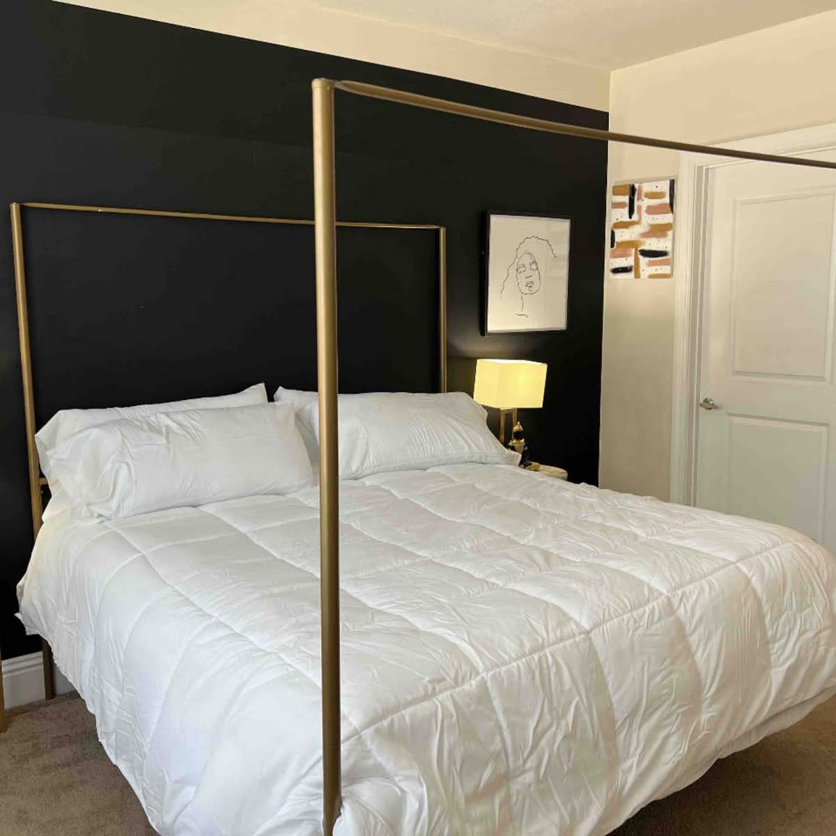 A neatly arranged bedroom with a four-poster bed, two bedside lamps, and a decorative wall art piece.