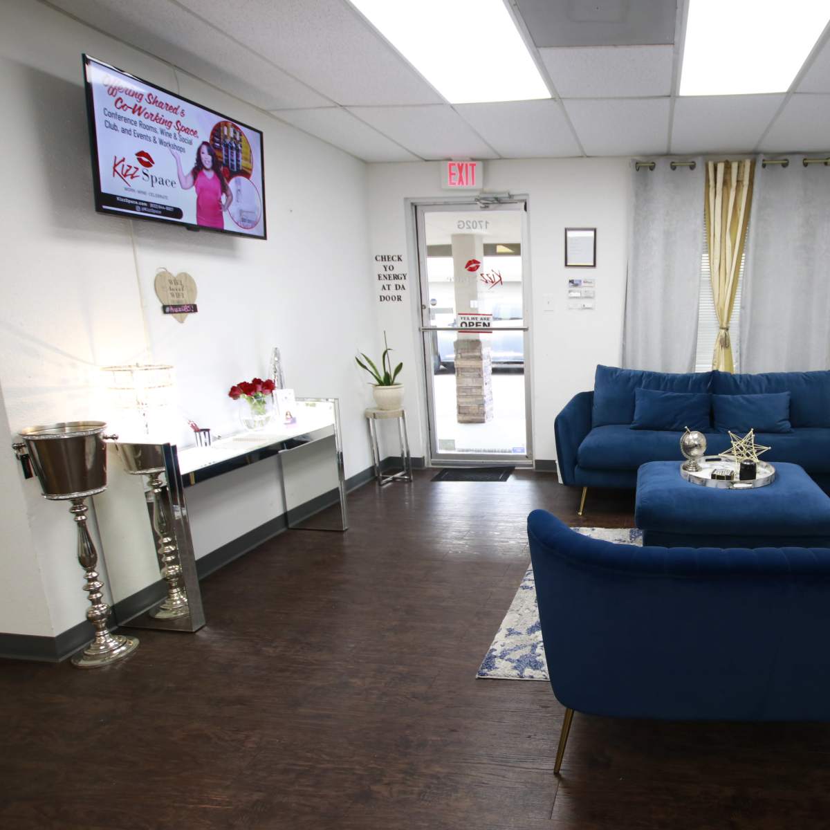 A modern waiting area with blue upholstered furniture, a decorative table, and a glass door leading outside.