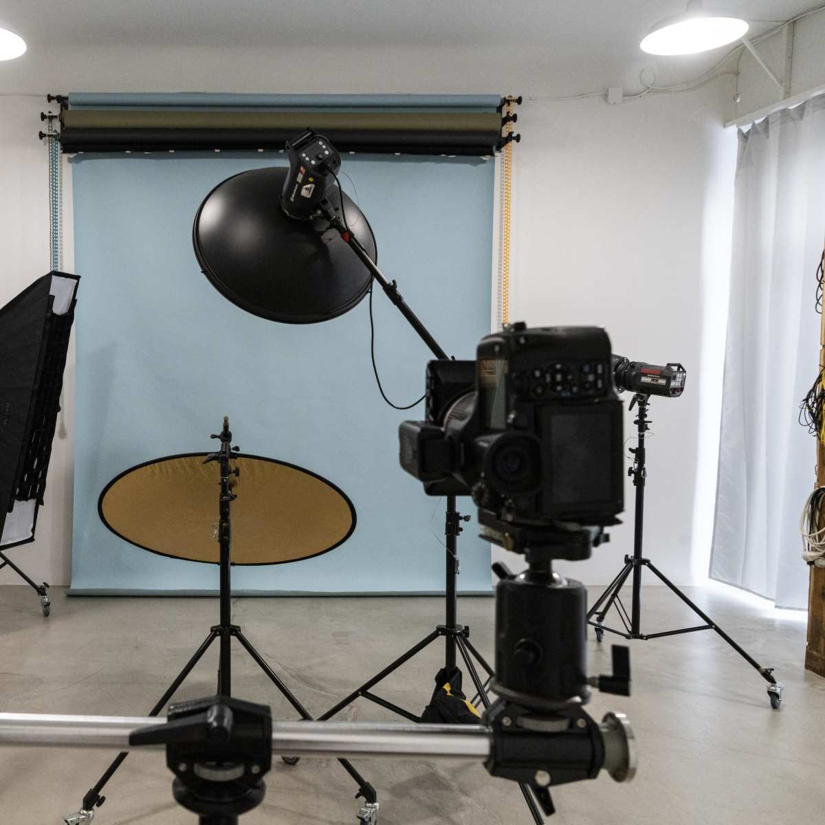 A photography studio setup with several cameras, lighting equipment, and a blue backdrop.