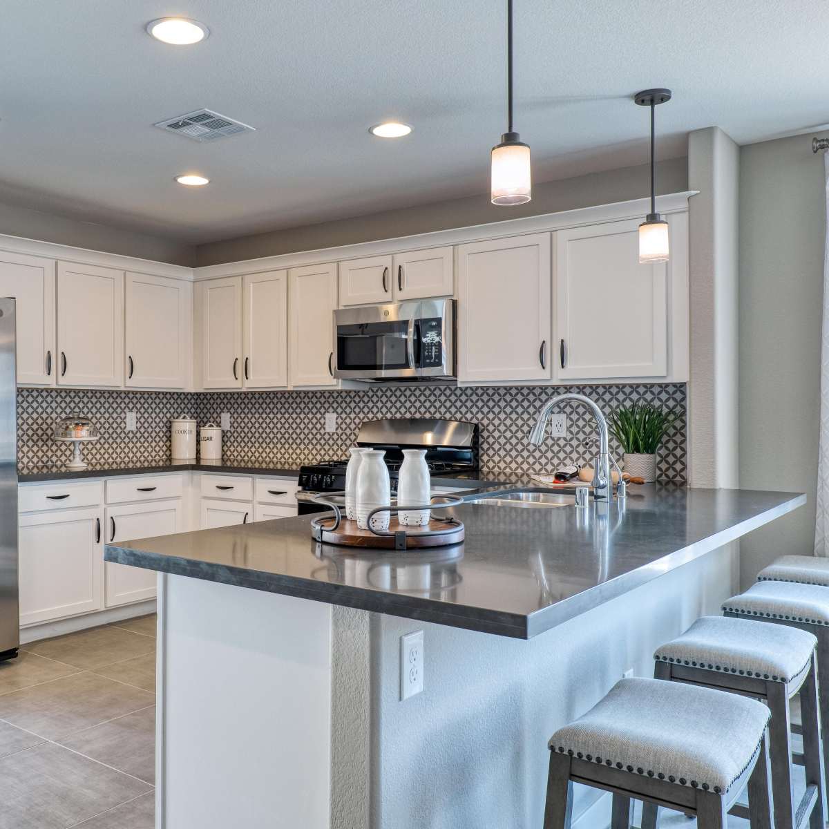 A modern kitchen with white cabinets, stainless steel appliances, and a large island with bar stools.