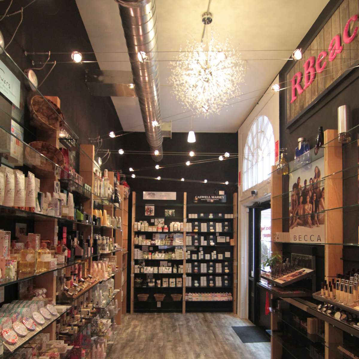 A well-organized store interior with shelves filled with various products, including beauty items and candles, and a prominent display at the entrance.