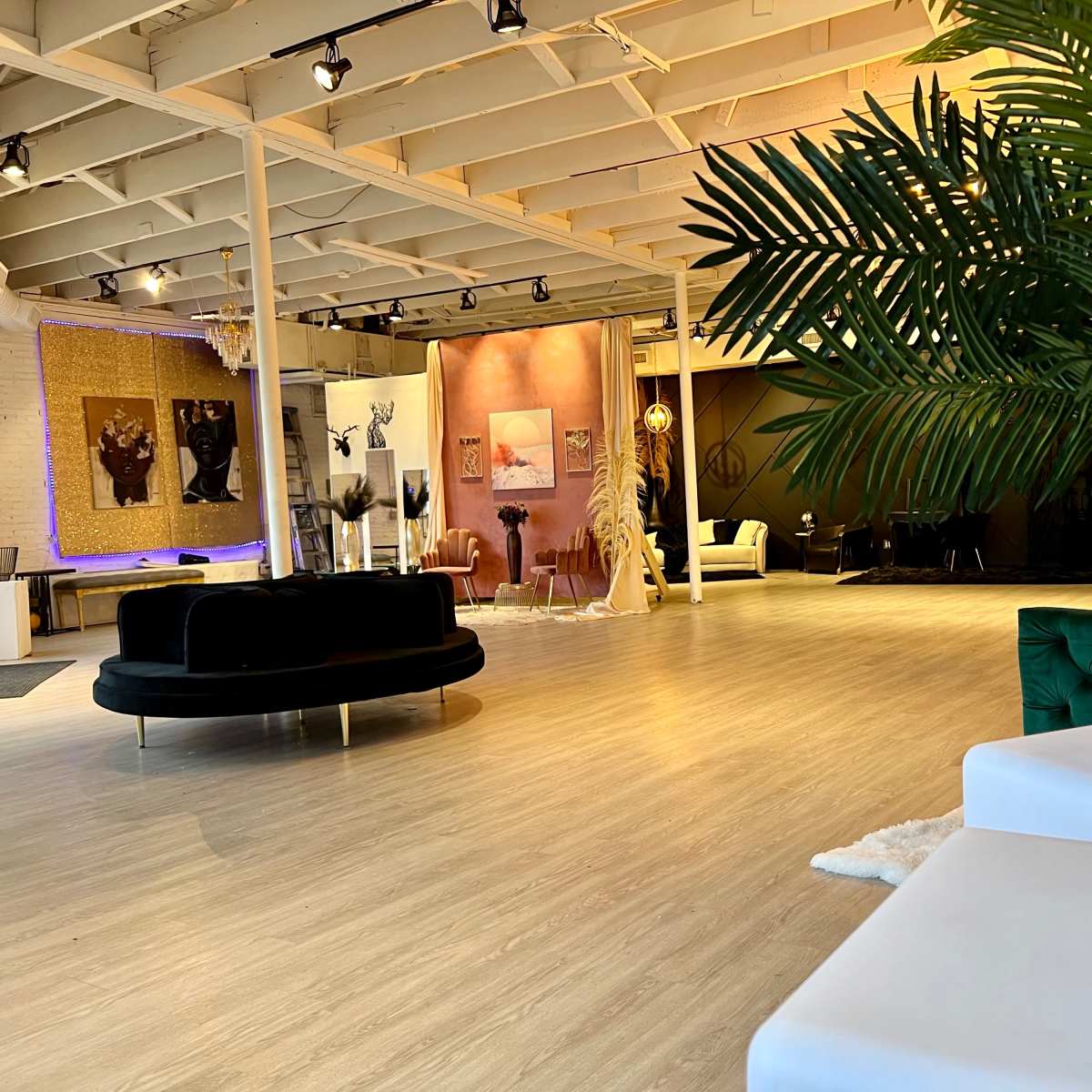 A spacious, modern interior with various seating areas, decorative plants, and vibrant wall art.