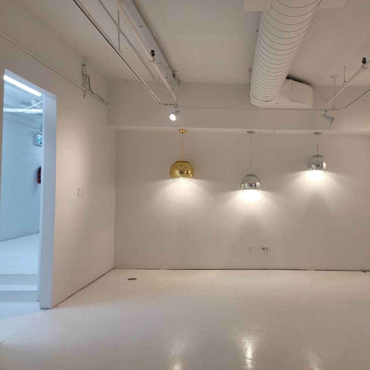 A minimalist white room with three pendant lights hanging from the ceiling.