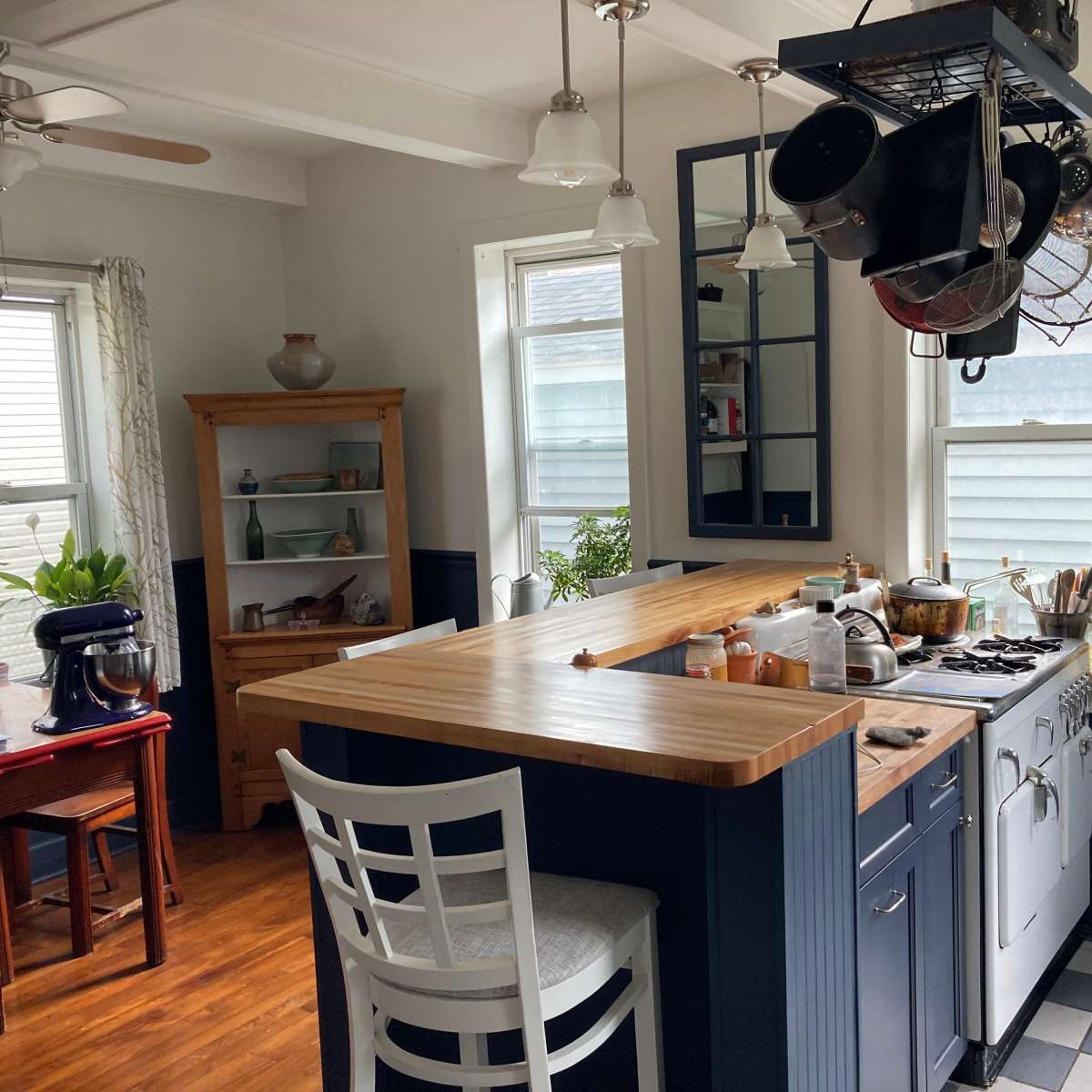 A spacious kitchen features a wooden countertop with cookware hanging above, a dining area with a small table, and a retro mixer on the counter.