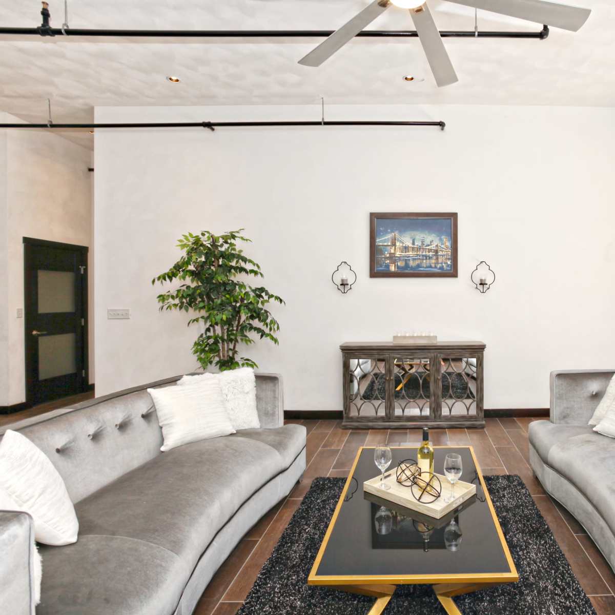 A modern living room with two gray sofas facing each other, a coffee table at the center, and a decorative wall art above a console table.