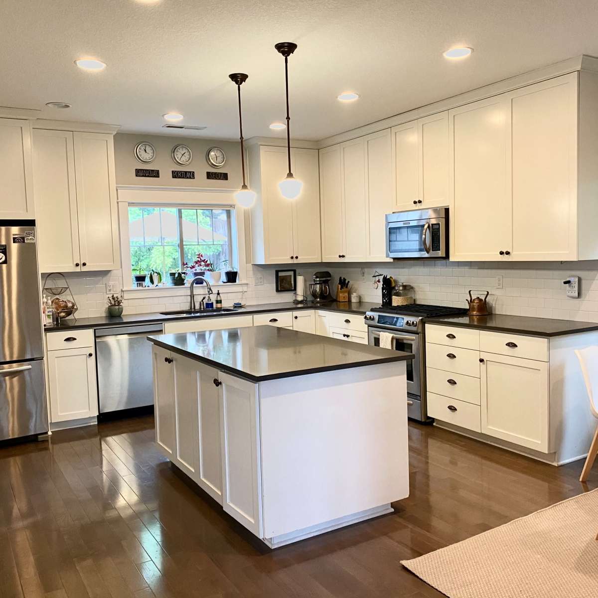 A modern kitchen with white cabinets, stainless steel appliances, and a central island with seating, alongside a small dining area.