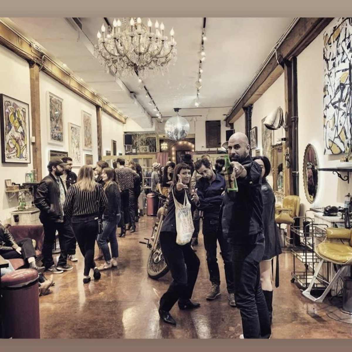 A lively art gallery features people socializing and interacting amidst various artworks and furnishings.