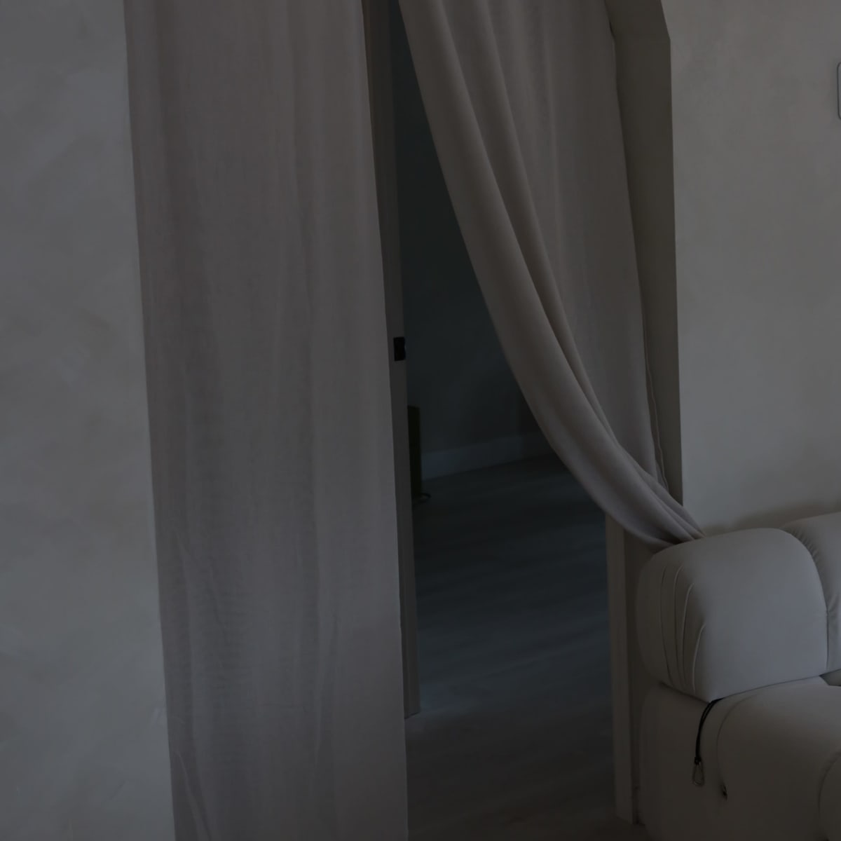 A light-colored curtain hangs in an archway, partially revealing a room beyond.