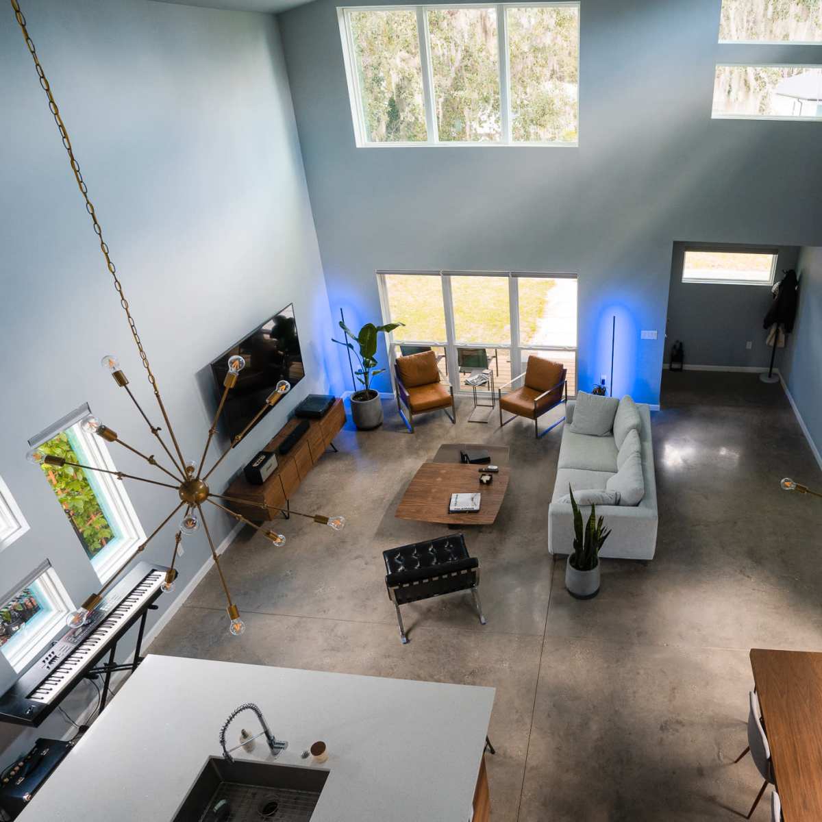 A spacious, modern living area featuring a sectional sofa, dining table, and large windows that provide natural light.
