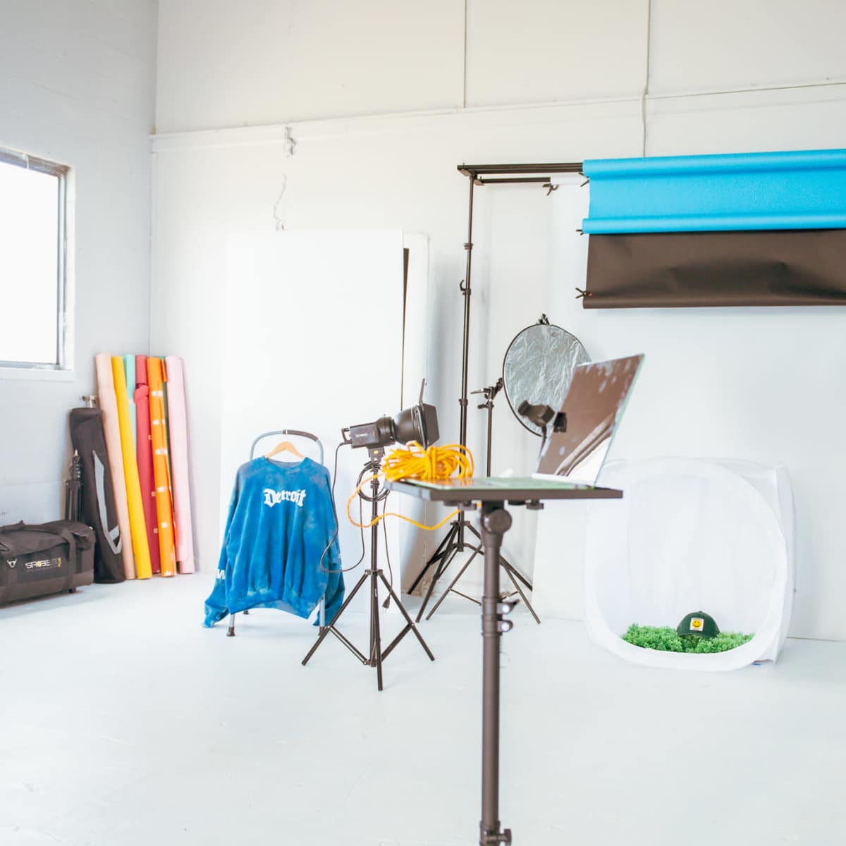 A photography studio setup is shown, featuring backdrops, lighting equipment, a table, and various props.