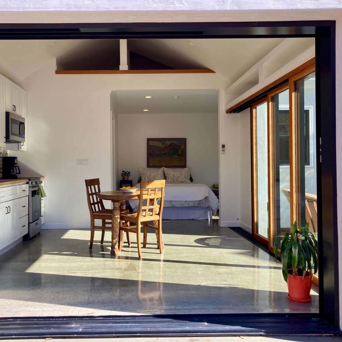 A modern kitchen and living space with a dining table are visible through a large open window.