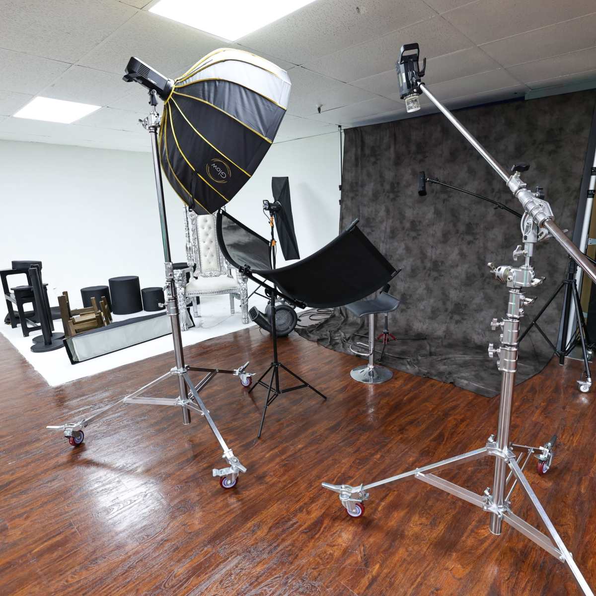 A photography studio setup with various lighting equipment and props arranged in a spacious area.