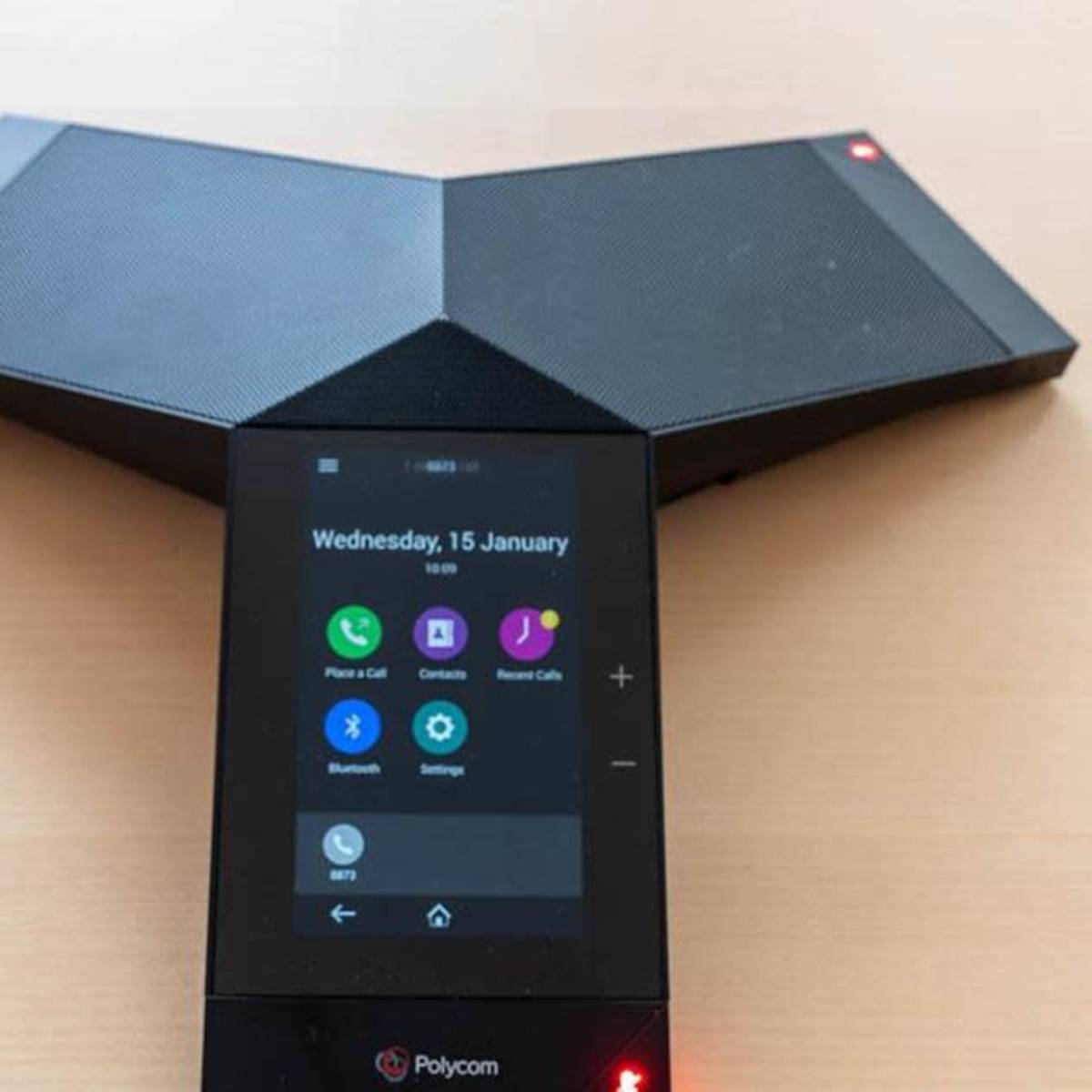 A Polycom conference phone with a digital display and two angled speaker components.