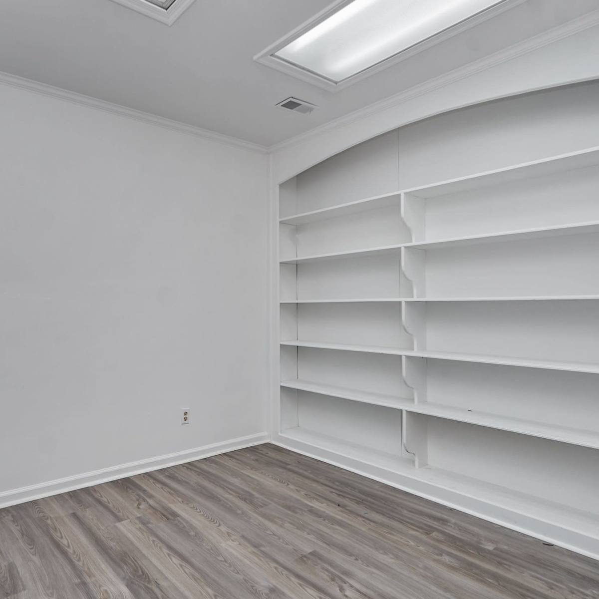 Aempty room with white walls and built-in white shelves on either side.