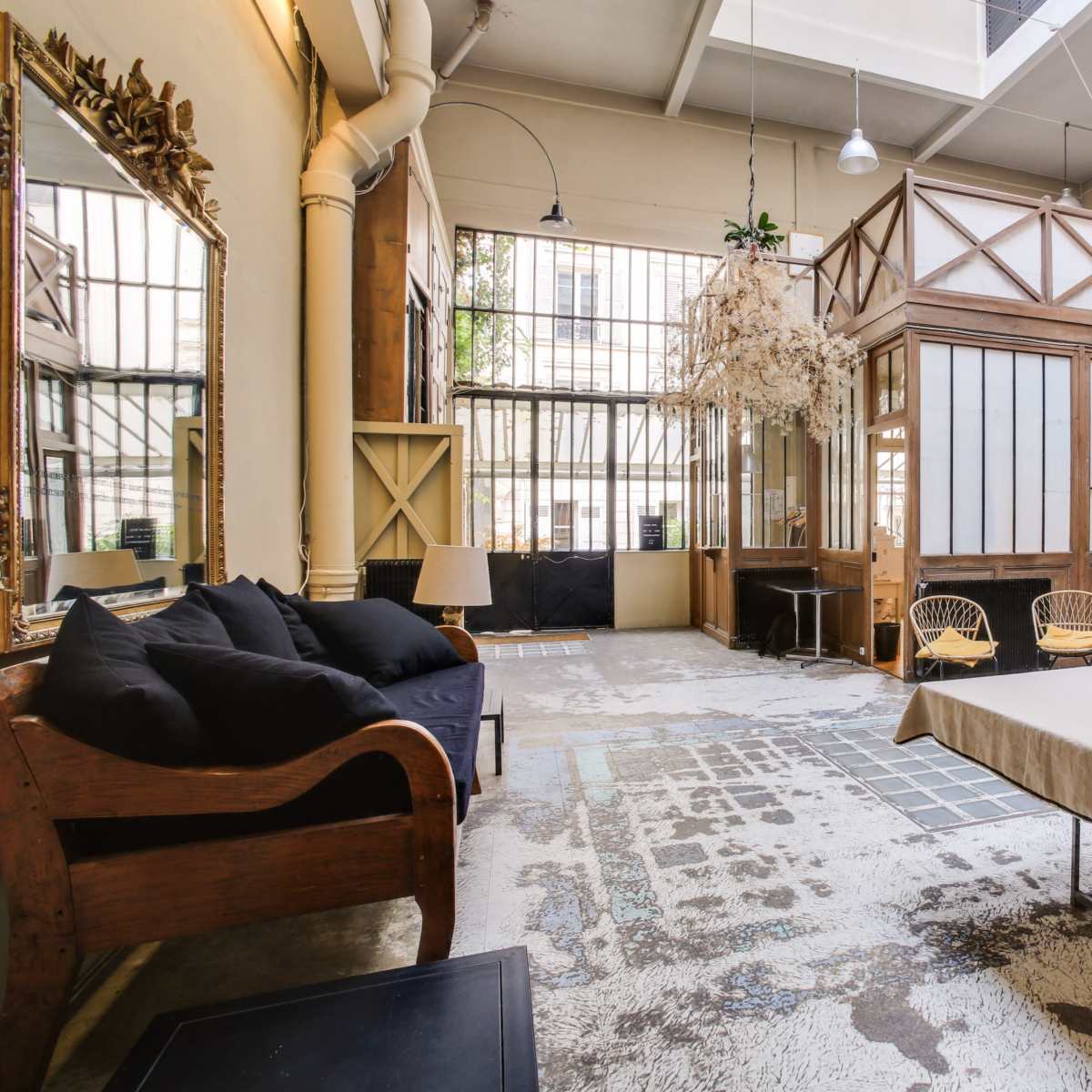 An open, spacious interior with wooden details, large windows, and a minimalist furniture arrangement, including a couch and a table.
