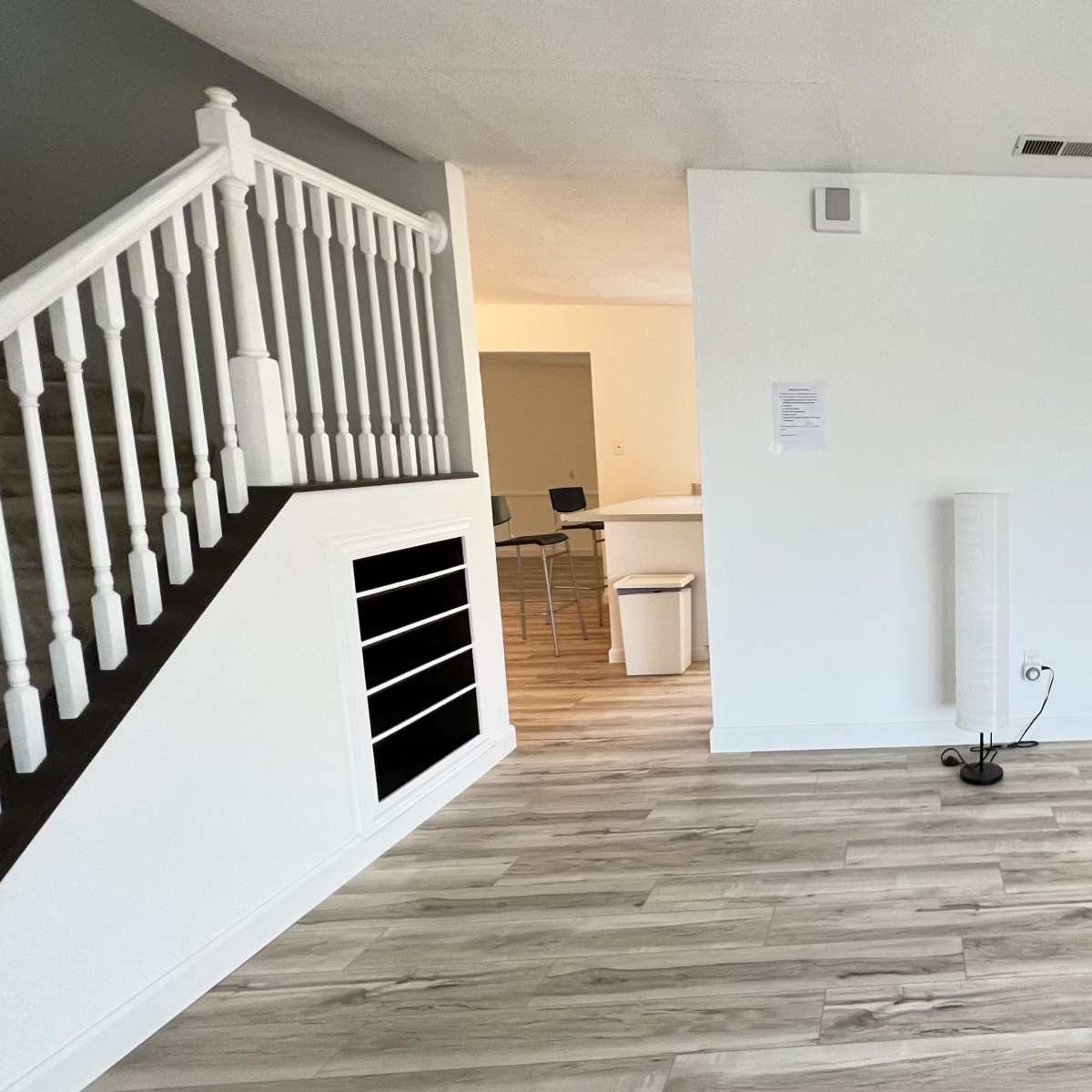 A spacious living area with a staircase on the left and a large window allowing natural light to enter.