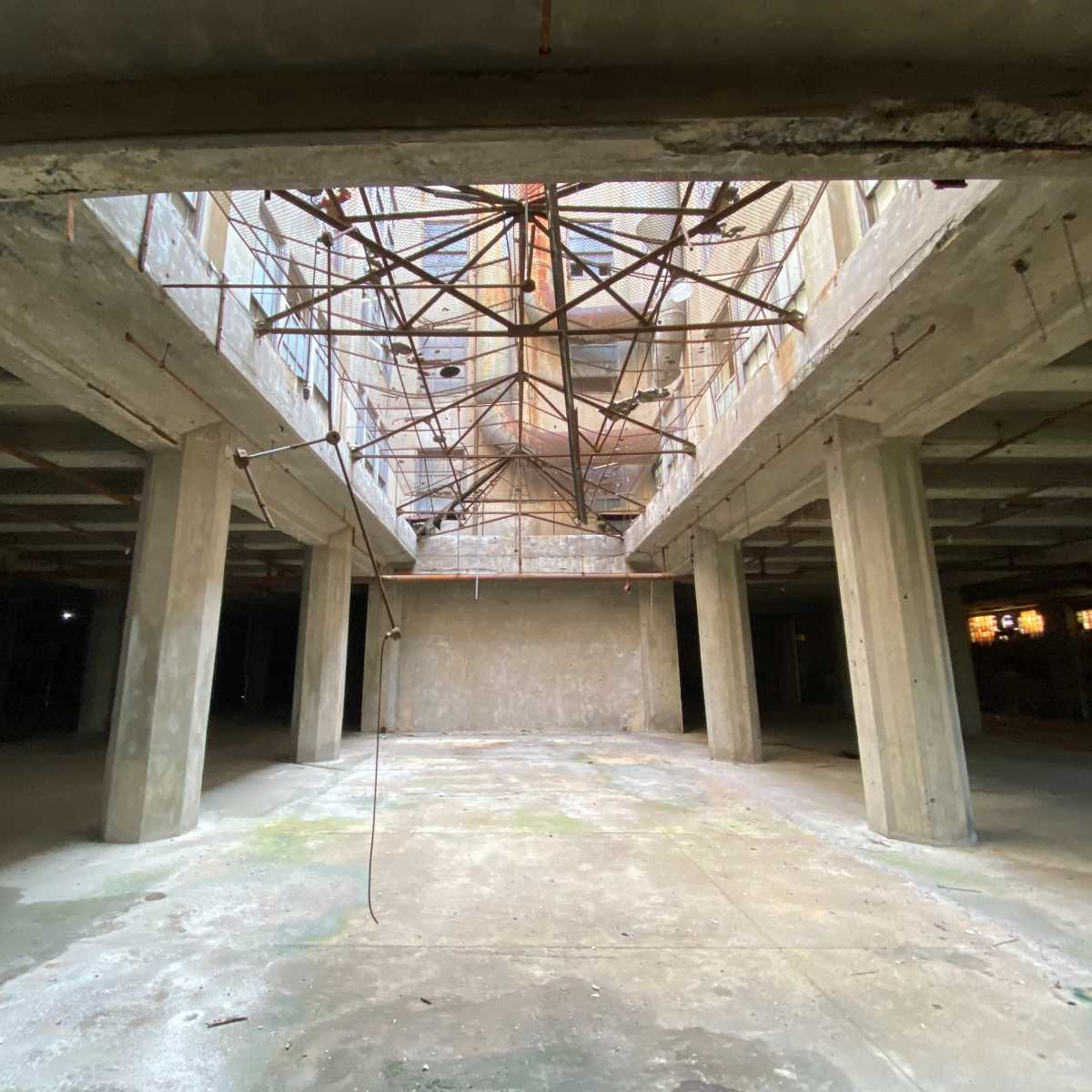An empty, unfinished building interior with concrete pillars and exposed structural framing above.