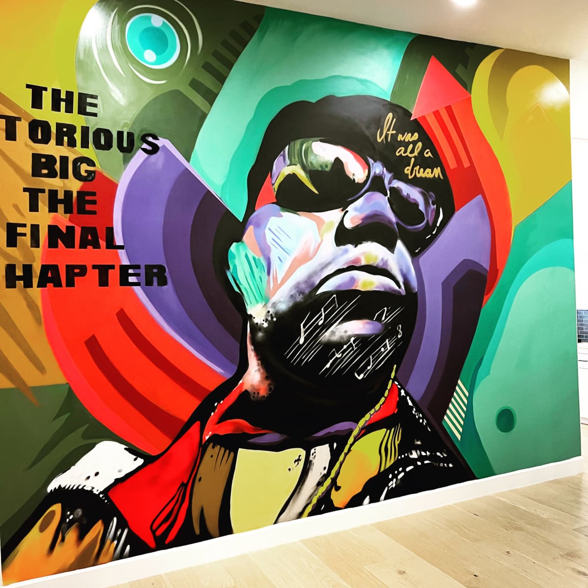 A colorful mural of a bespectacled figure with vibrant geometric shapes and text, featuring "THE NOTORIOUS BIG" and "THE FINAL CHAPTER."