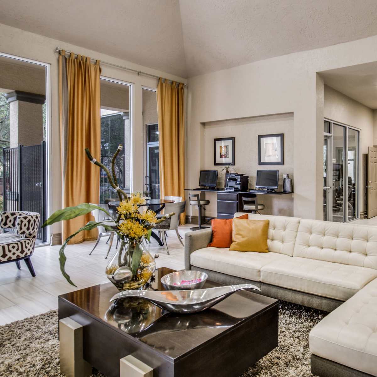 A modern living space featuring a sectional couch, a low table, and a kitchen area with bar seating.