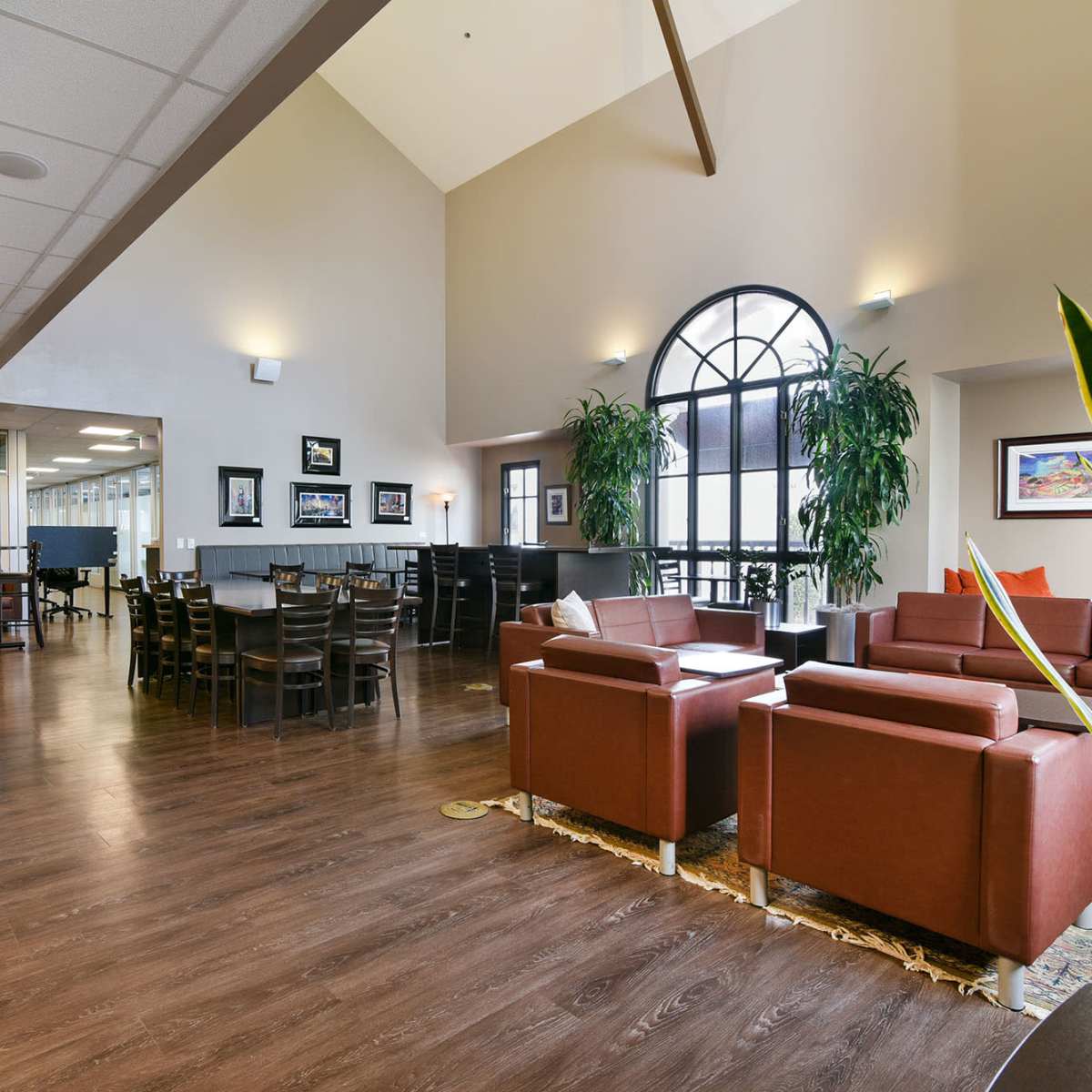 A spacious dining area with seating arrangements, including tables and chairs, along with lounge seating and large windows.