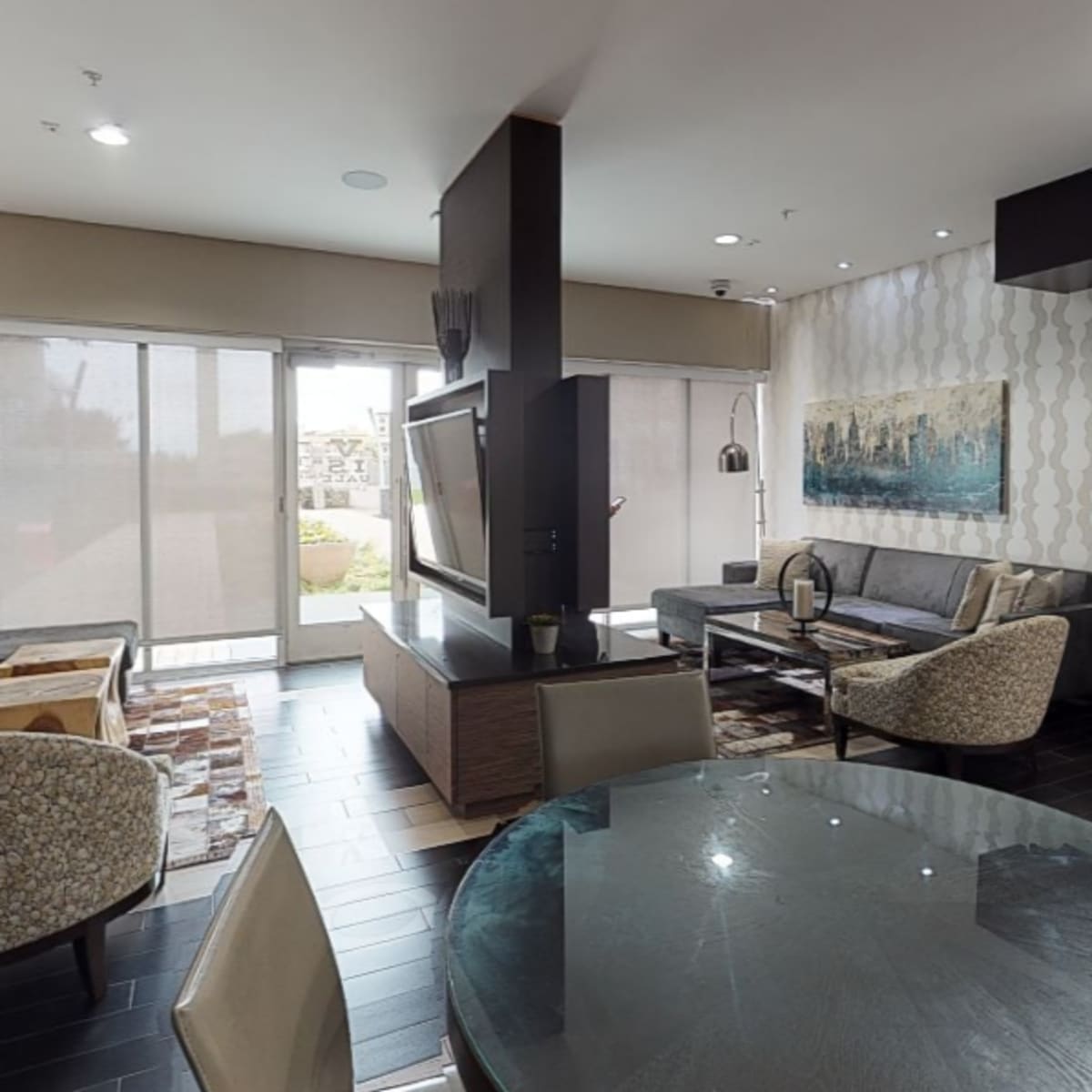 A modern living area with a seating arrangement, a dining table, and a large window providing natural light.