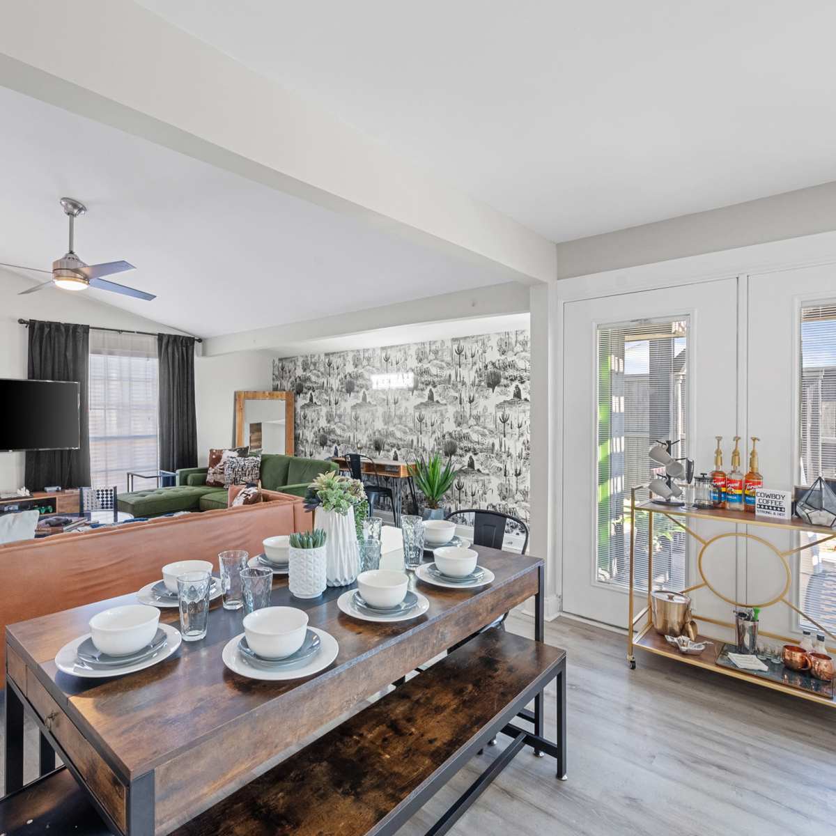 A modern living room with a seating area, a wall-mounted television, and a dining table set for a meal.