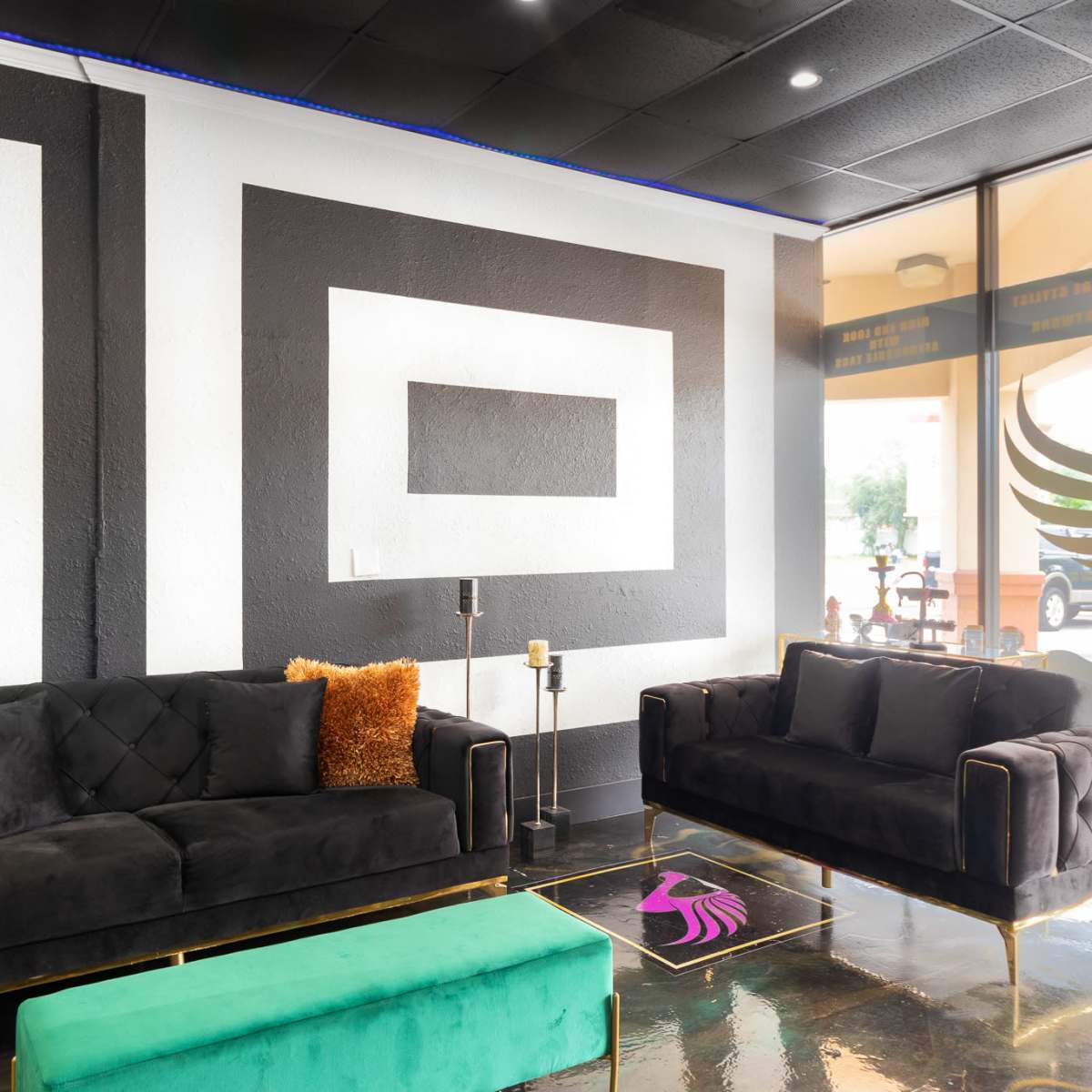 A modern lobby with black and white geometric wall designs, two black sofas, and a green coffee table.