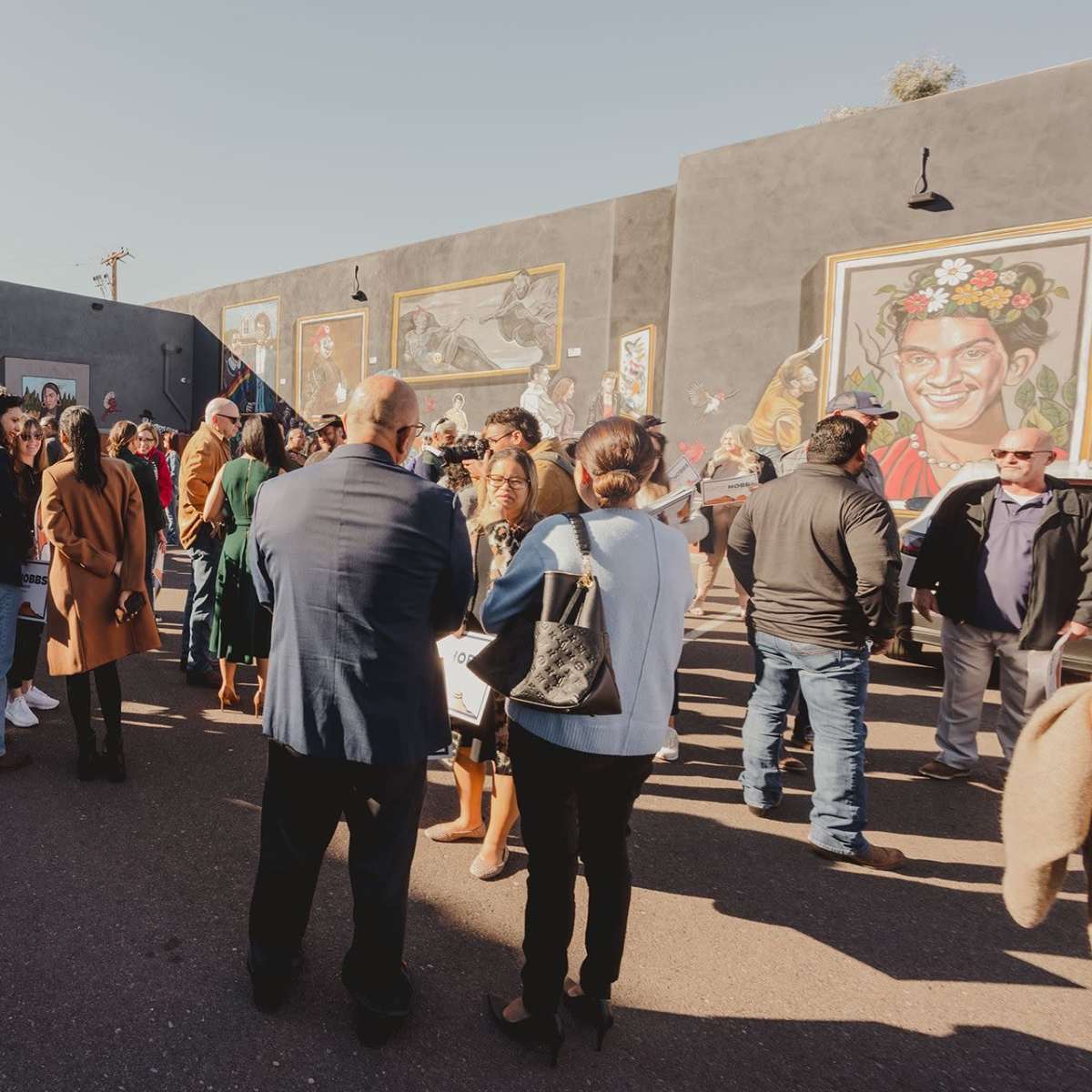 A large crowd gathers outside a venue with colorful murals on the walls and a sign that reads "Luna."