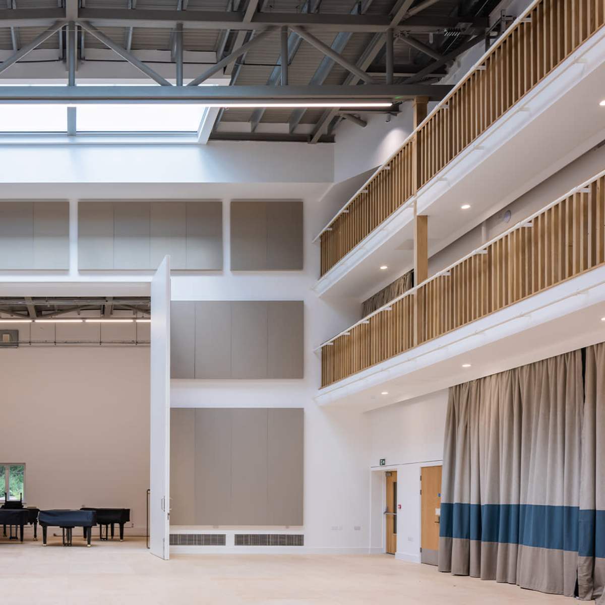 A spacious room with high ceilings, large foldable panels, and a grand piano placed in the center.