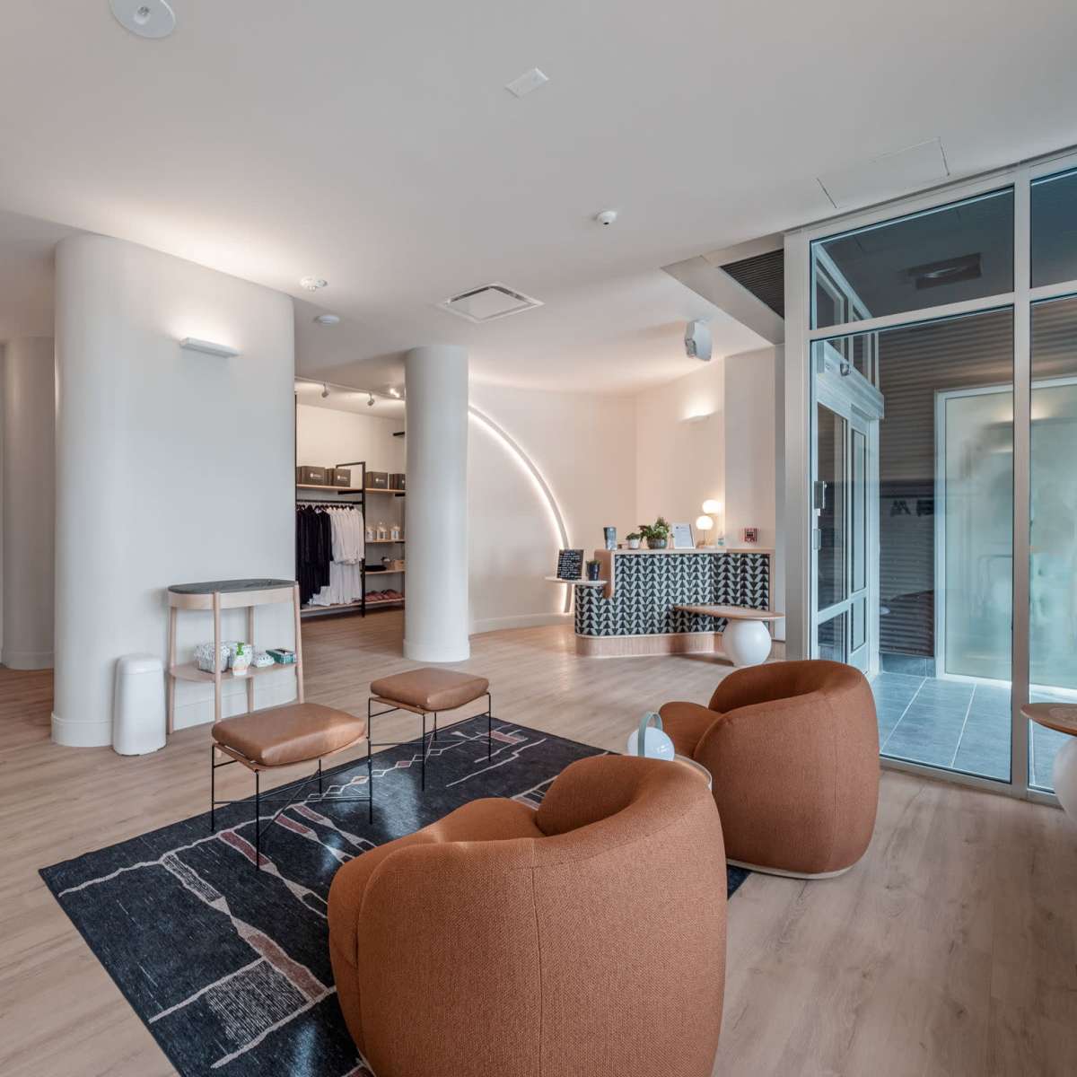 A modern lobby with curved seating, wooden floors, and a check-in area featuring a patterned desk.