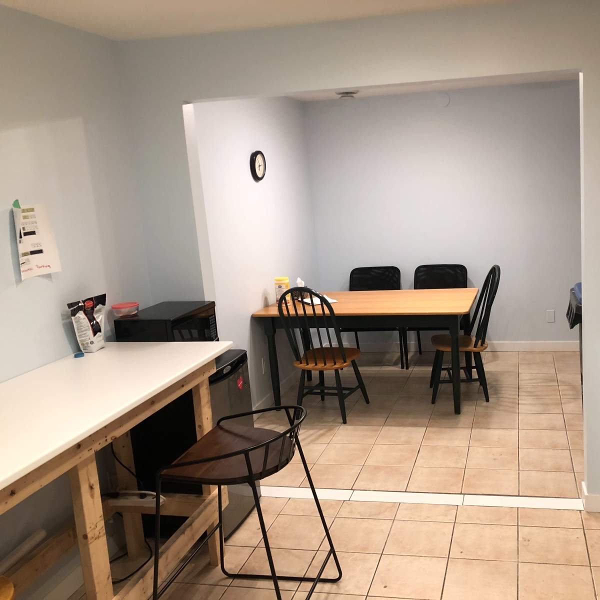 A kitchen area features a countertop and appliances on one side, with a dining table and chairs in an adjacent space.