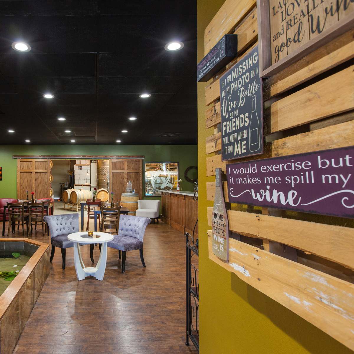 A cozy interior of a wine-themed establishment featuring stone walls, a small water feature, and seating areas with wooden decor.