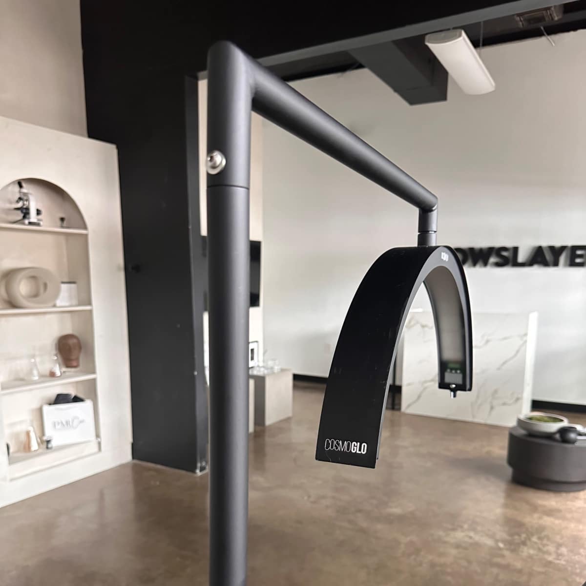 A modern black lamp with an arched lighthead mounted on a sleek, minimalistic stand in an interior space.