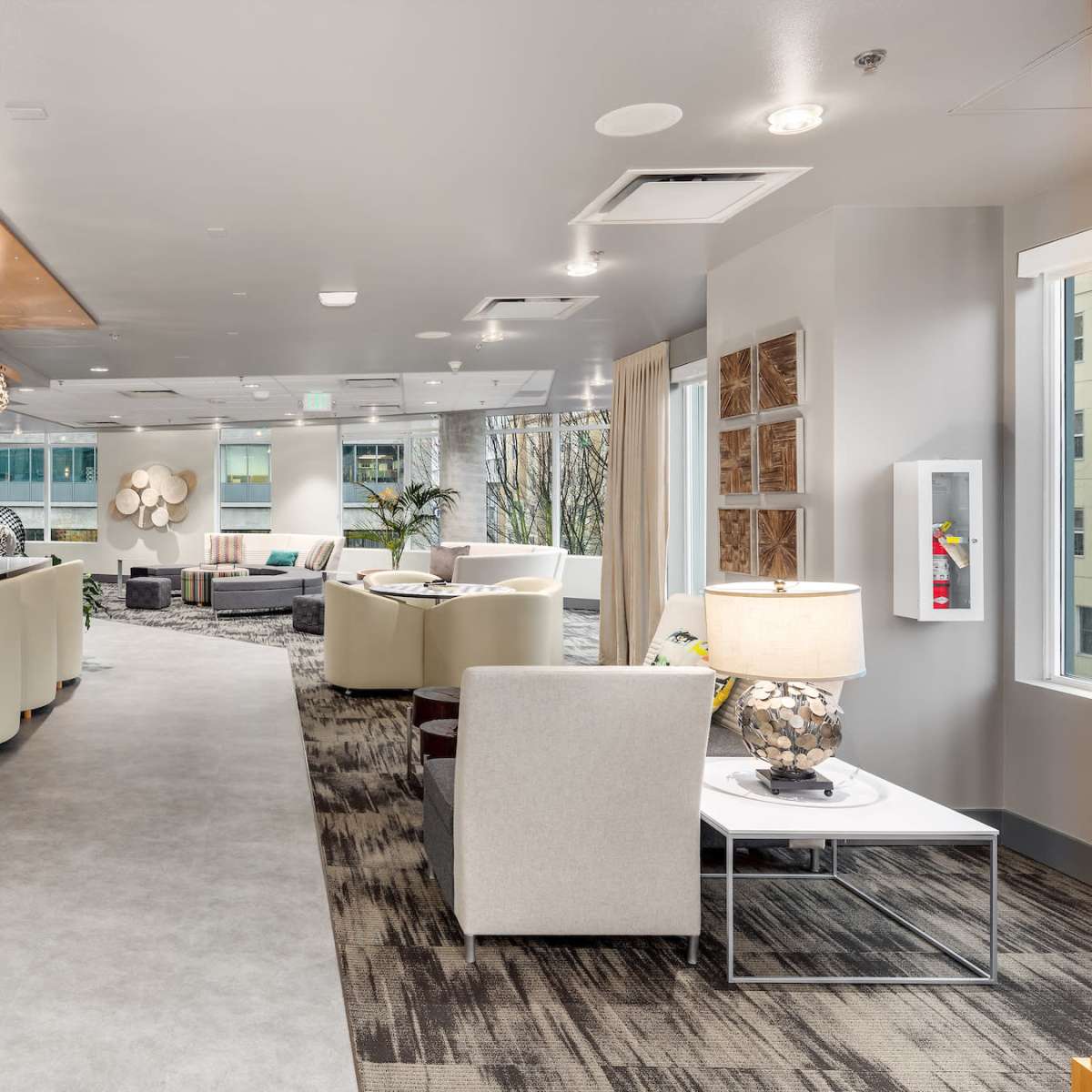 A modern lobby area features a long reception desk, comfortable seating arrangements, and decorative lighting fixtures.