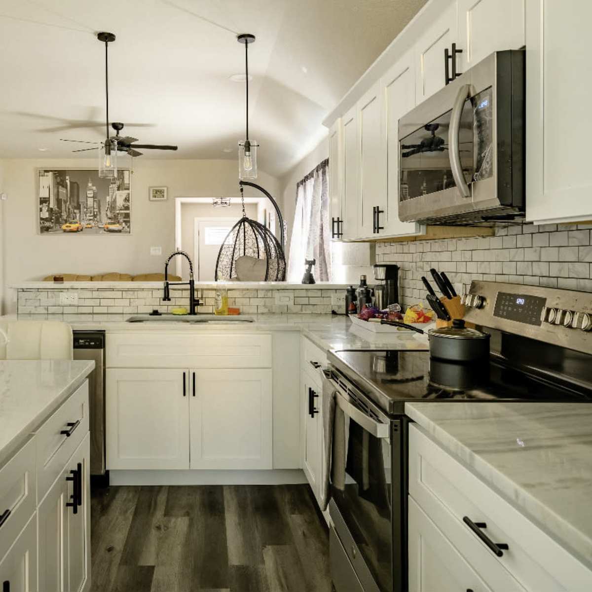A modern kitchen with white cabinetry, stainless steel appliances, and a marble countertop.