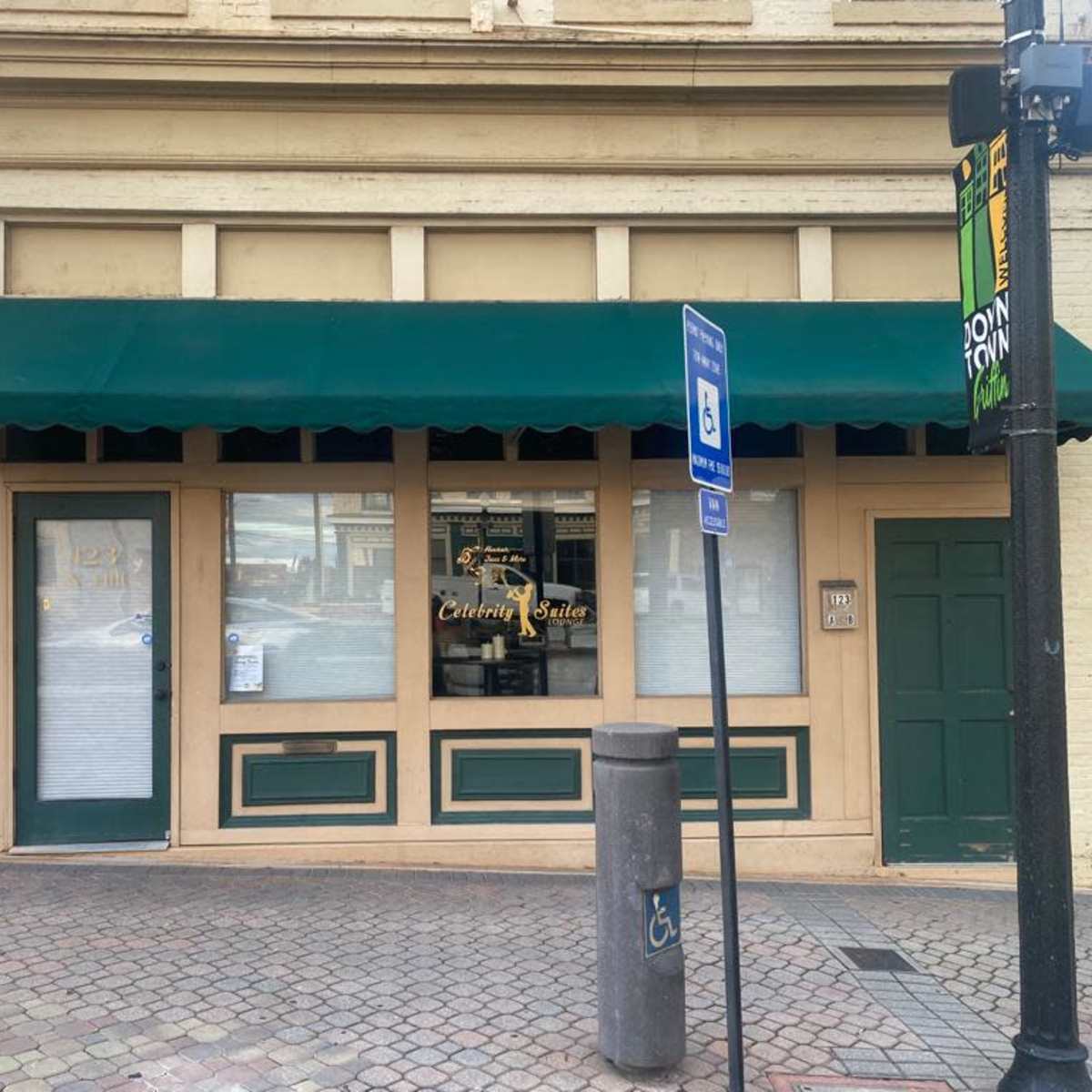 A storefront with a green awning and large windows, located at the corner of a street.