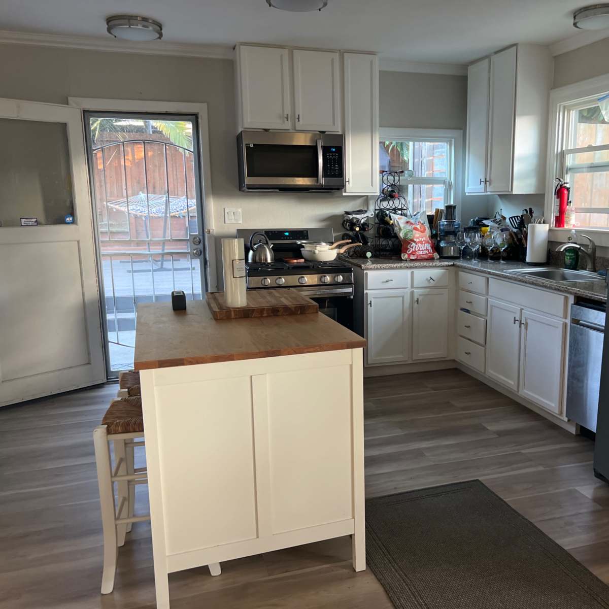 A kitchen with white cabinetry, stainless steel appliances, and a central island with a wooden countertop.