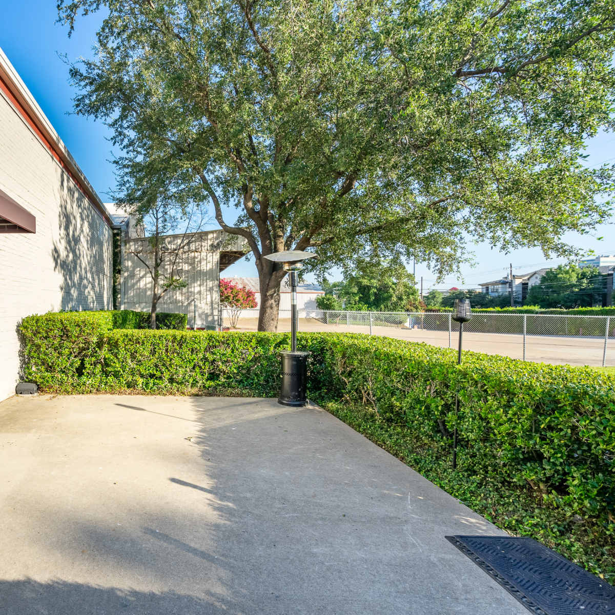 An exterior view of an office building entrance with a landscaped area and a paved walkway.