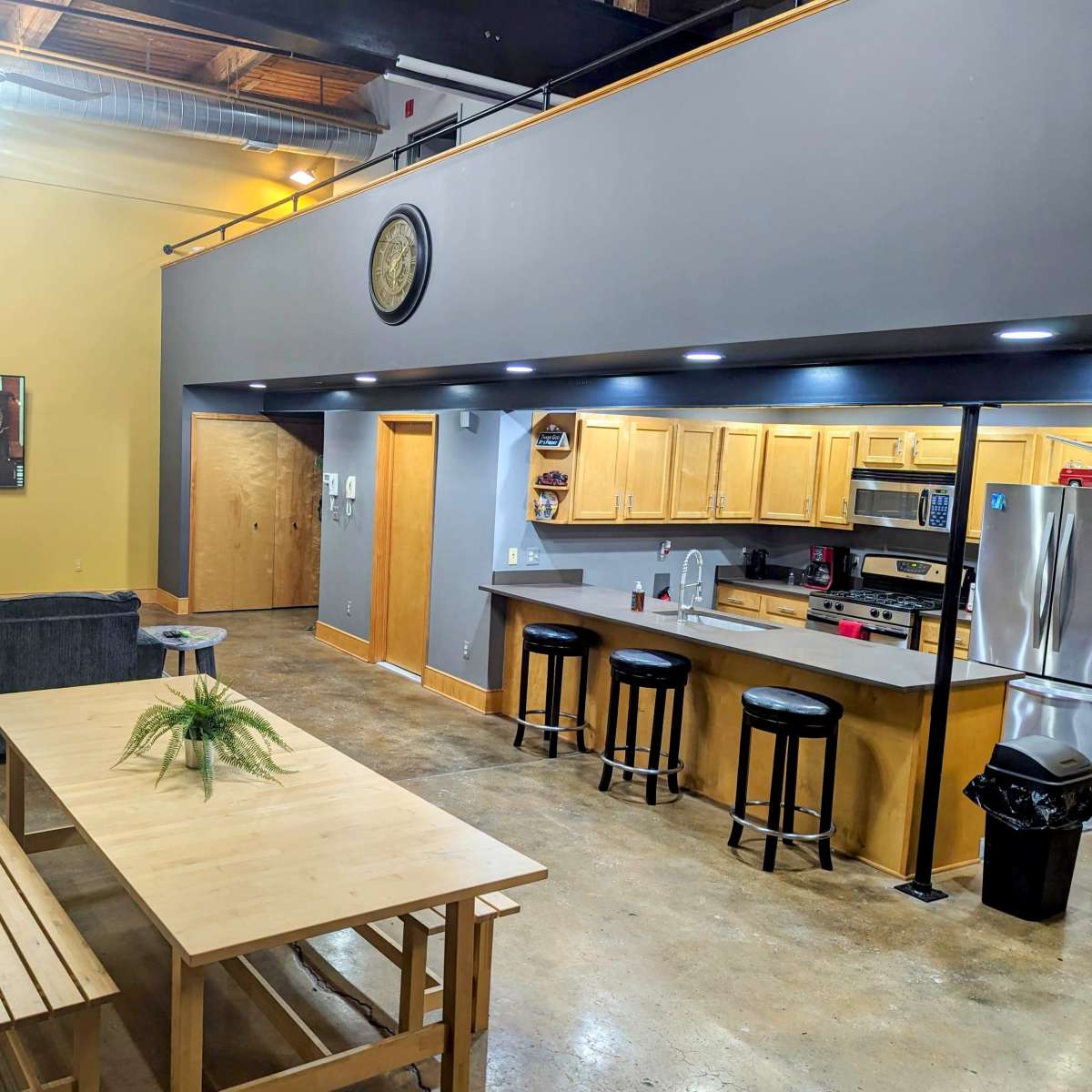 A spacious, modern living area featuring a kitchen with wooden cabinets, a dining table, and a seating area with a sofa.