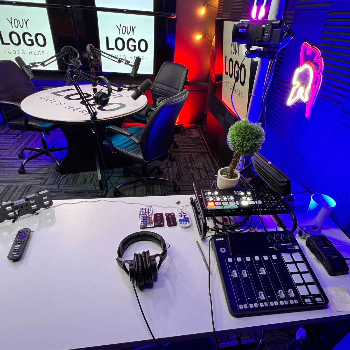 A recording studio setup with a round table, microphones, audio equipment, and a decorative plant on the table.