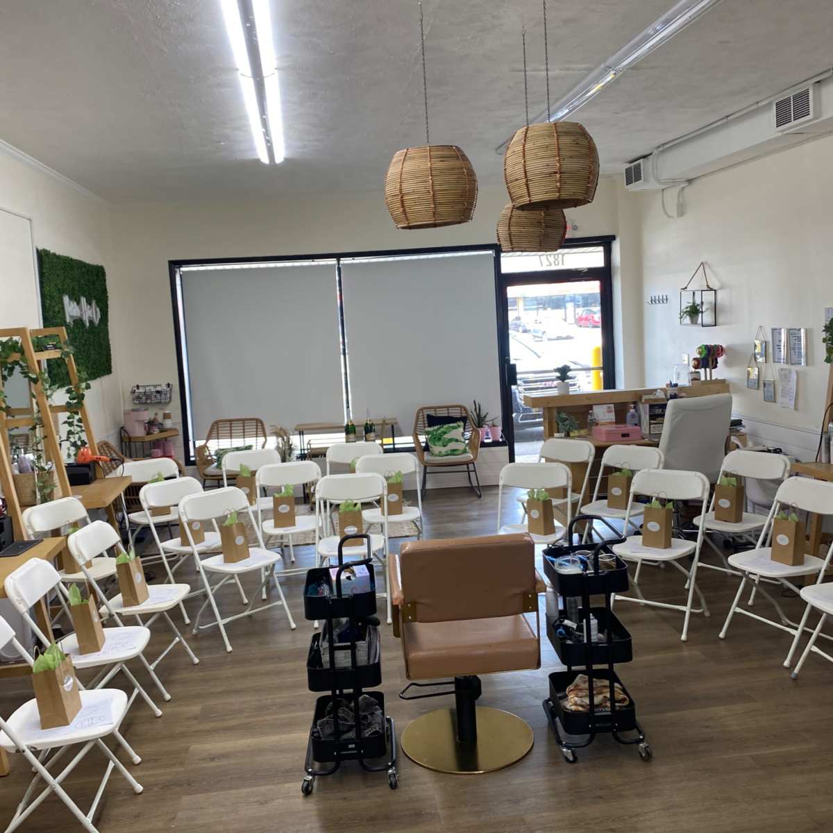 A brightly lit room is set up with white chairs arranged in a circle around a central seat, with hanging lanterns above and a decorative green wall in the background.