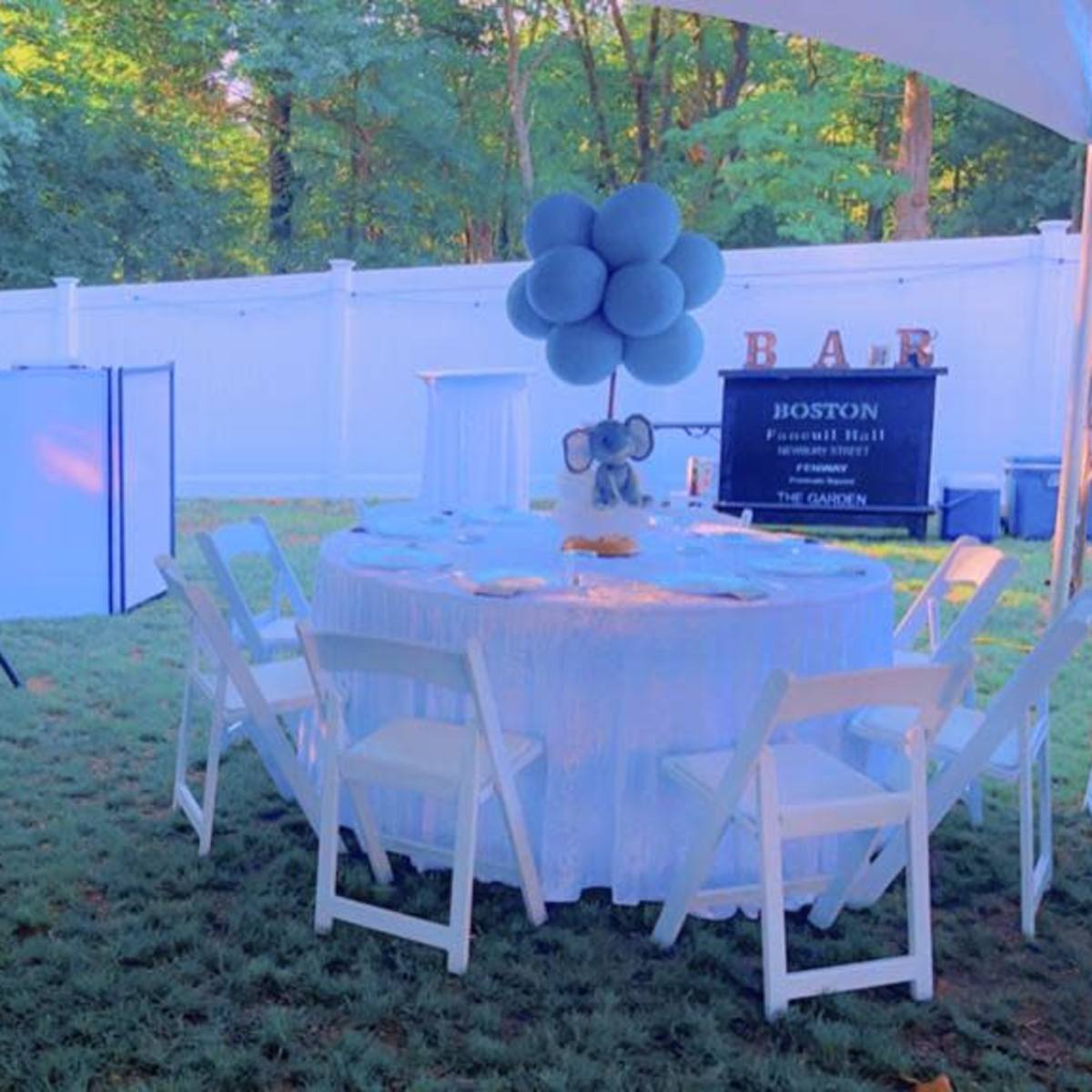 A garden party tent features a blue-themed setup with a table and chairs, an elephant decoration, and a dessert cart.