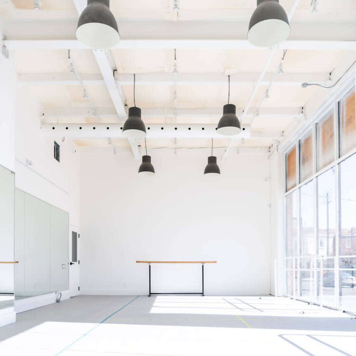 An empty, bright studio space with large windows, high ceilings, and a central table.
