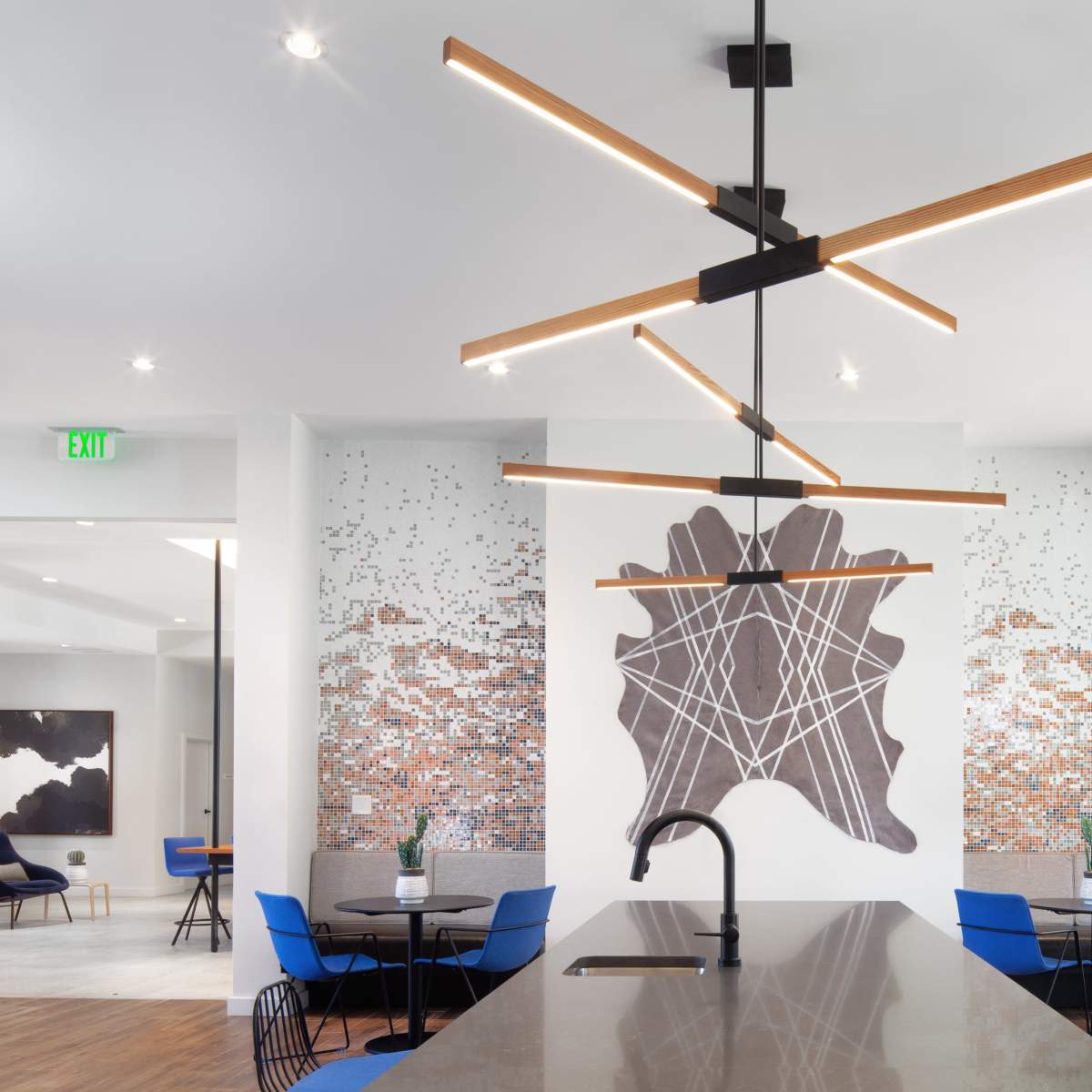 A modern dining area with a large island countertop, contemporary lighting fixtures, and a mural of abstract shapes on the wall.