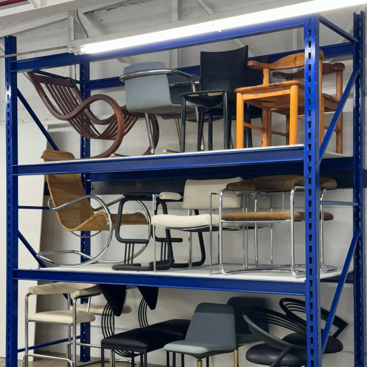 A blue industrial shelving unit displays various types of chairs arranged across three levels.