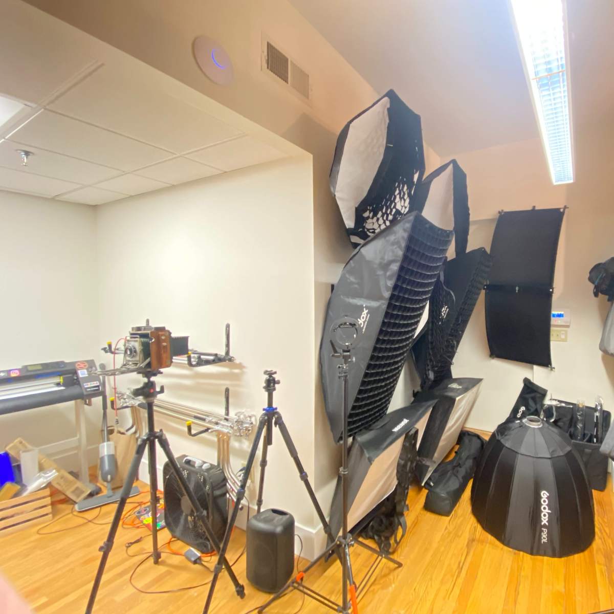 A photography studio is filled with various lighting equipment, backdrops, and stands arranged along the walls.