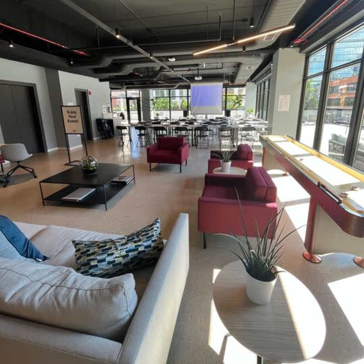A spacious, modern lounge area with seating, tables, and large windows allowing natural light in.