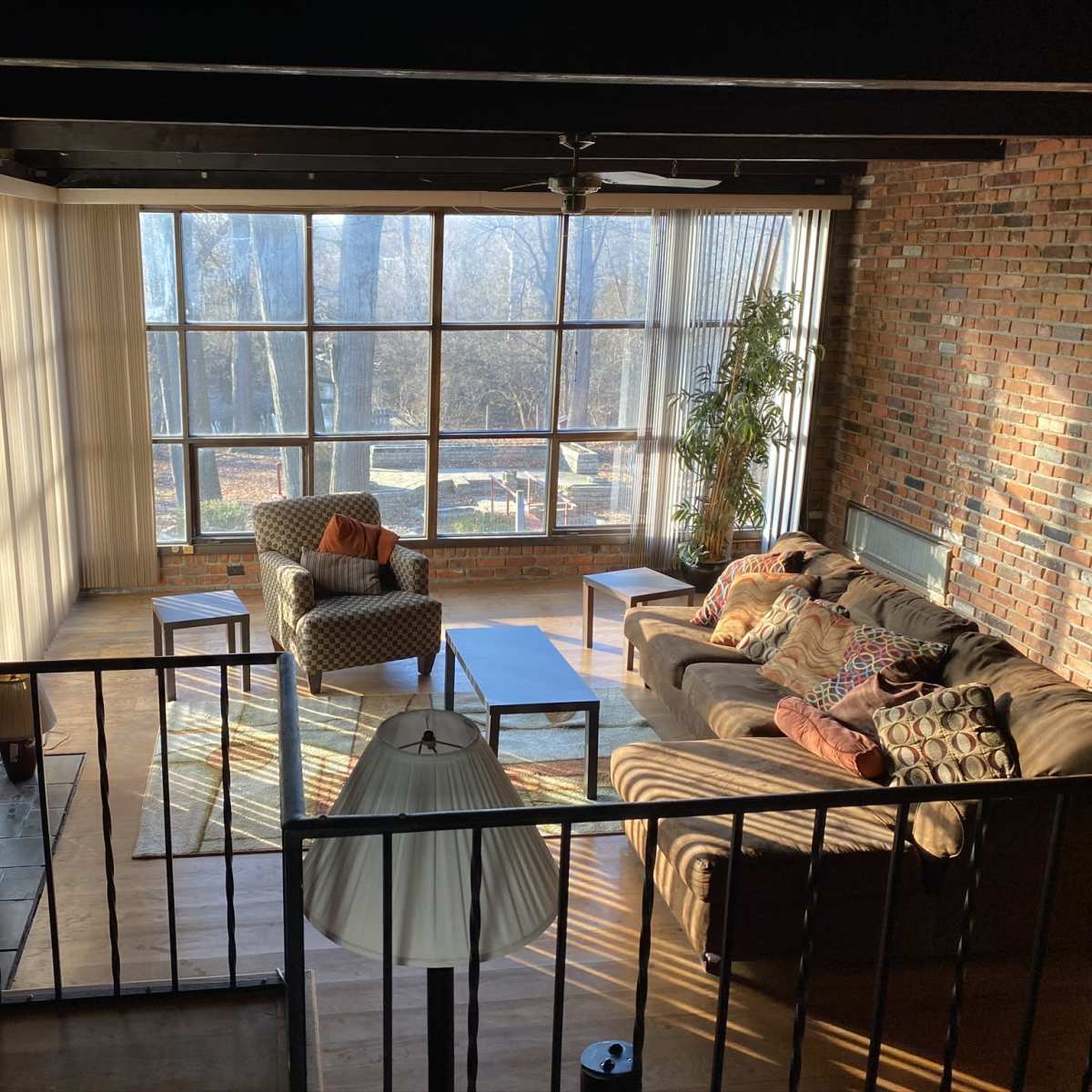 A spacious living room with large windows, a mix of seating options, a coffee table, and a view of a landscaped area outside.