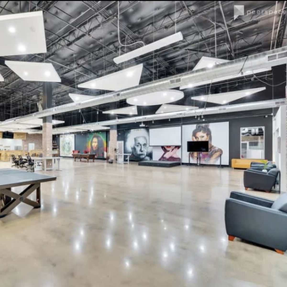 A large, modern open space with polished concrete floors, a billiards table, and various wall-mounted artworks.