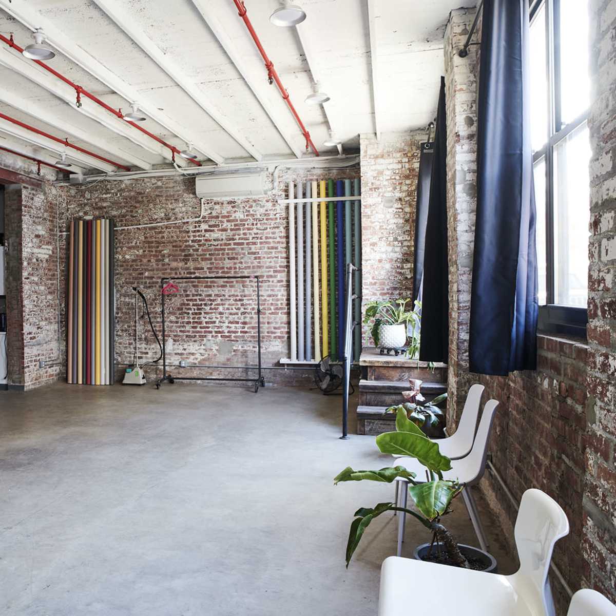 An industrial-style room with exposed brick walls, concrete flooring, and colorful vertical panels along one side.
